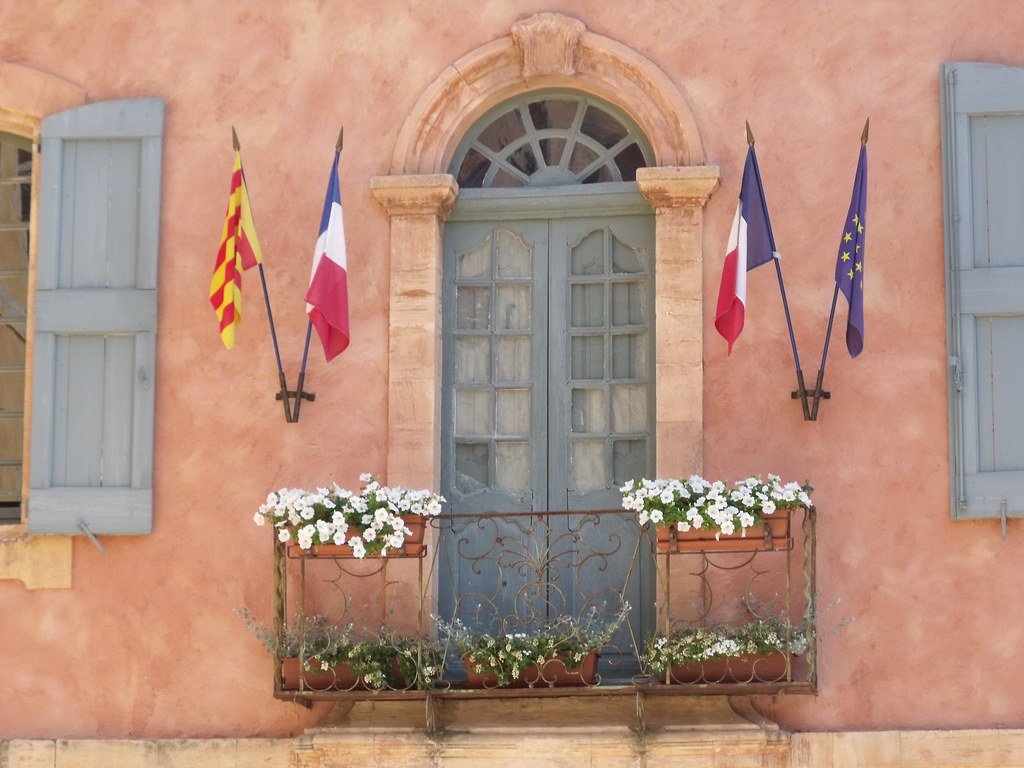 Balcon fleuri avec drapeau français, village de Roussillon